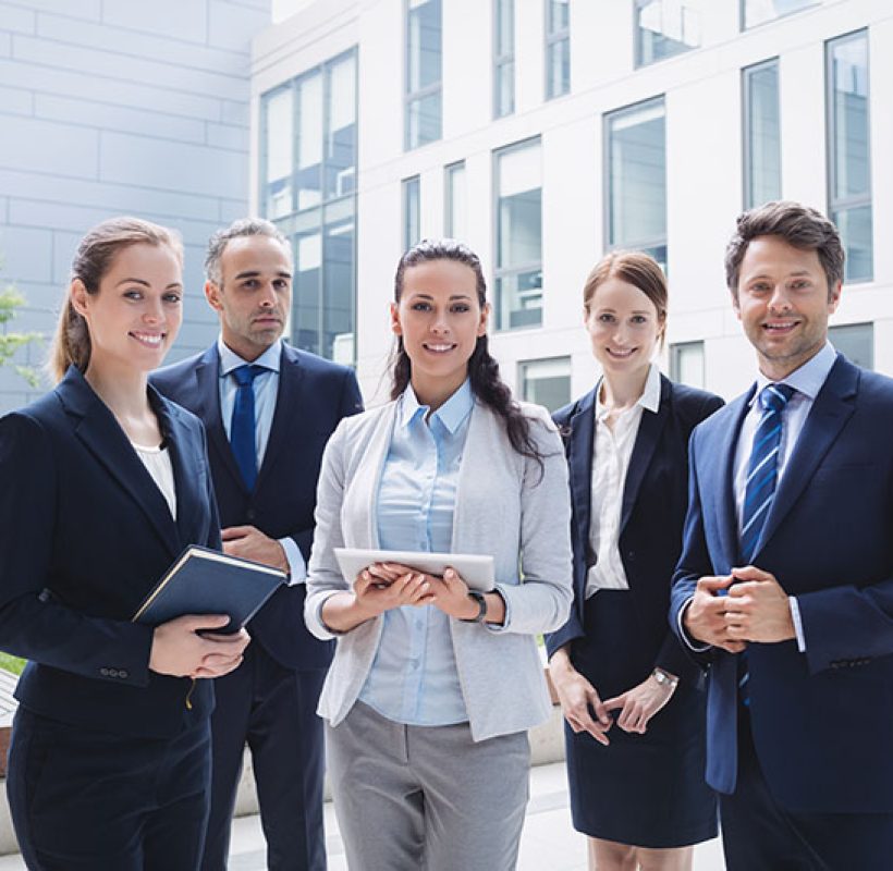 Portrait of confident businesspeople standing outside office building